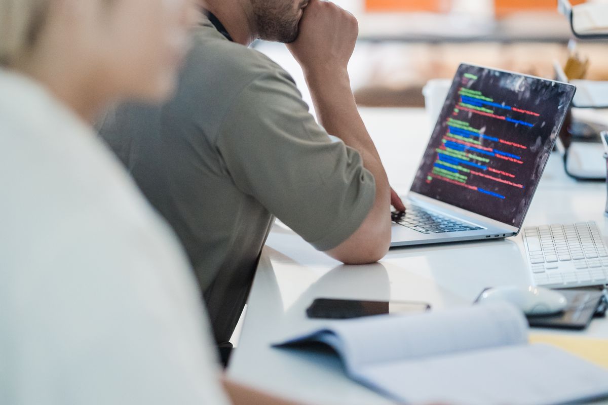 Two developers working through code together in an open-plan office