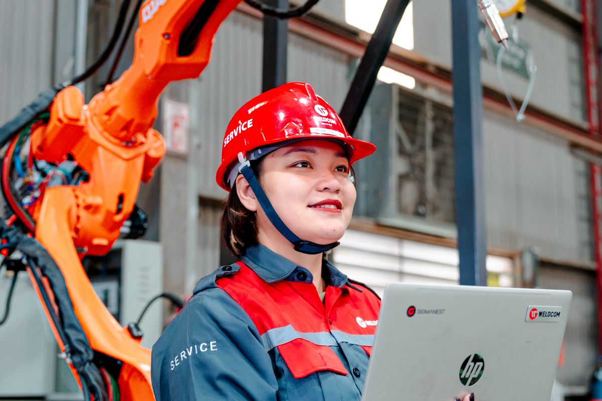 Engineer supervising robotic machinery on a factory floor
