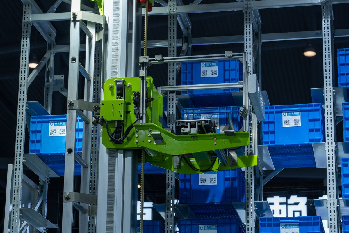 Robotic arm moving crates in an automated warehouse